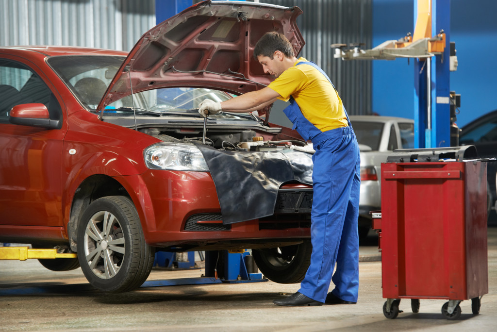 Young man tighten screws in a car using a spanner
