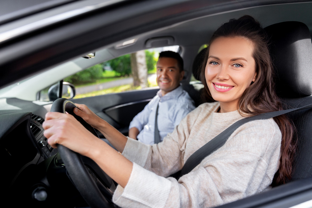 Young woman learning to drive with a driving school instructor.
