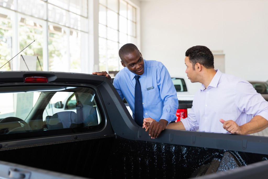 man discussing with male salesperson at a used truck dealership